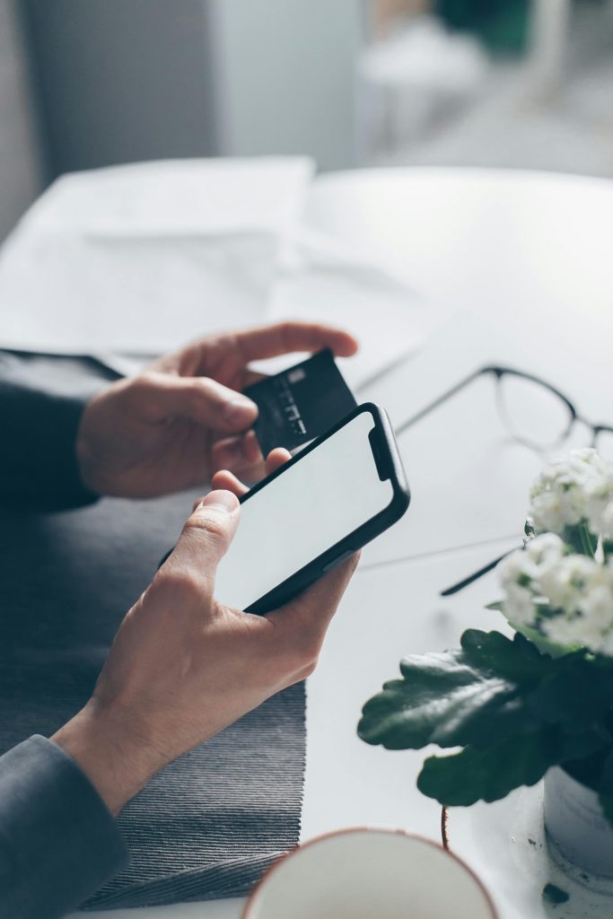 pexels-photo-7534801-7534801-683x1024-1 Close-up of hands holding a smartphone and a credit card, implying online payment.